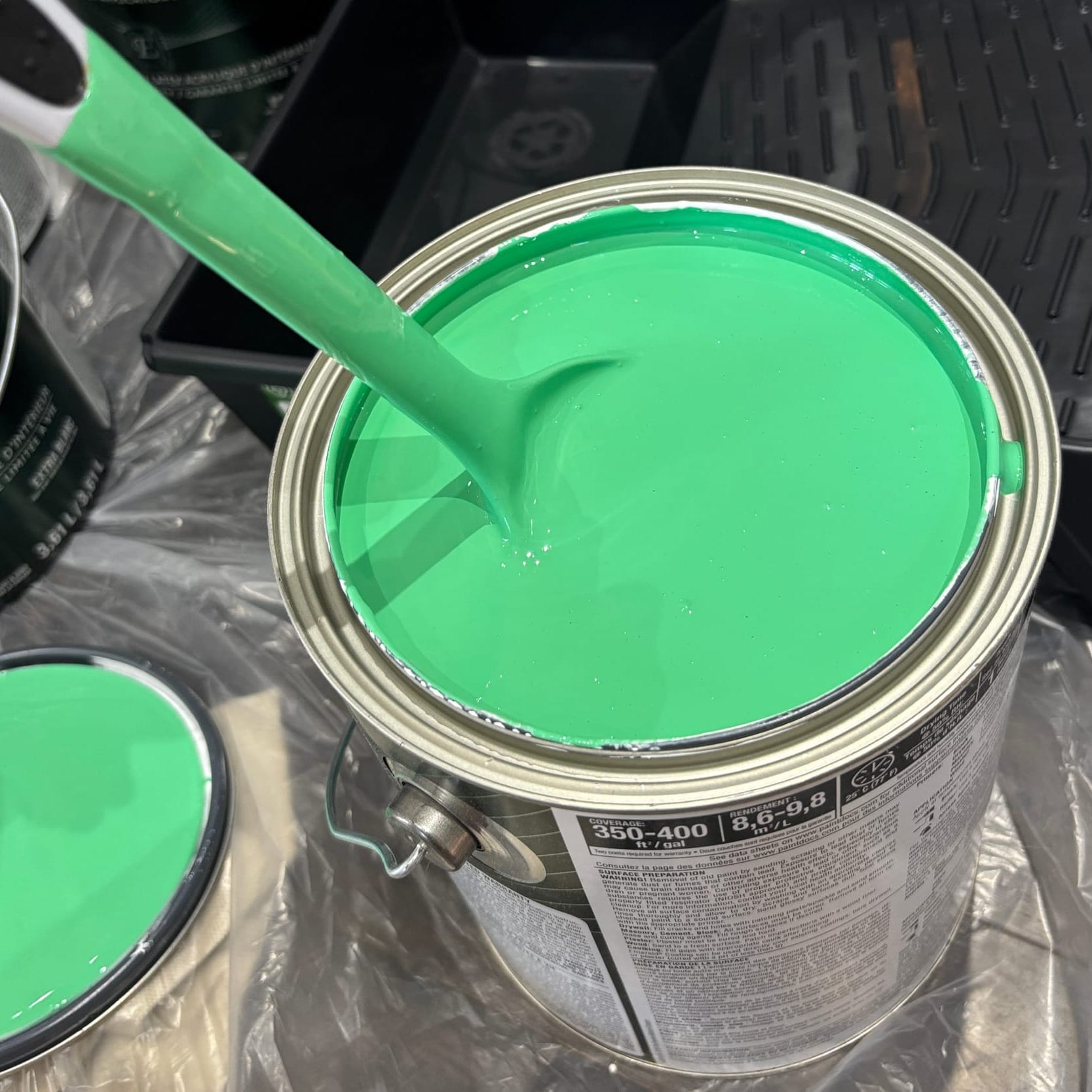 an open can of bright green paint, much more neon than the paint on the wall in the other picture